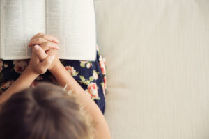 woman's hands folded over Bible in her lap