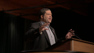 Keith Plummer at Chapel podium with hands raised