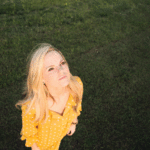 Photo of a blonde woman in a yellow dress staring up at the sky