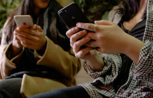 hands of two individuals who are each holding a cell phone