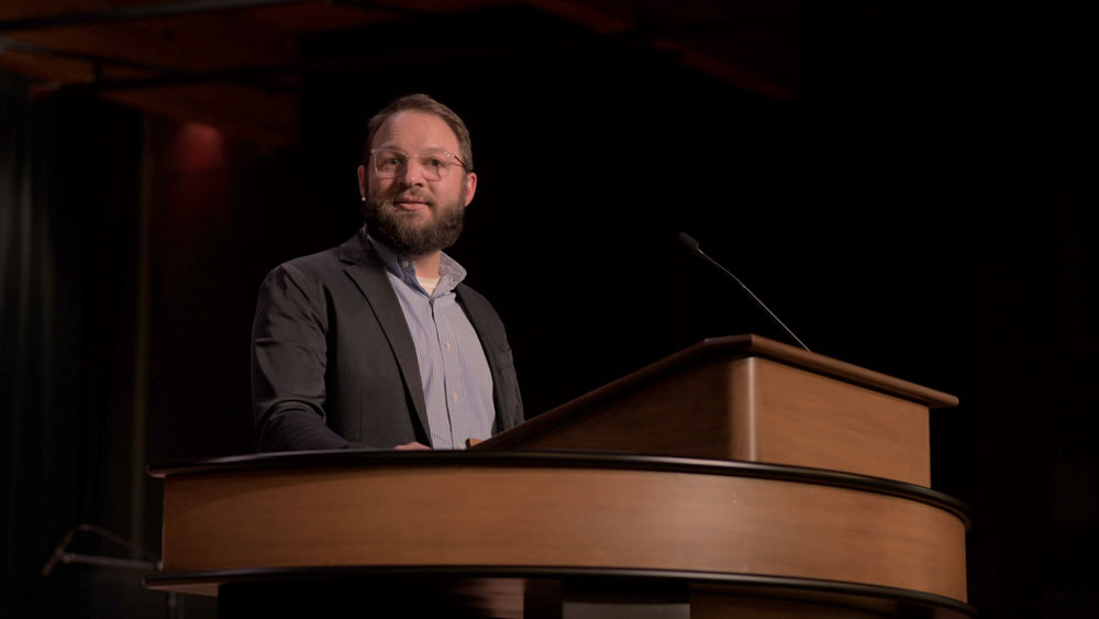 Ben Best standing at chapel podium, looking out to audience