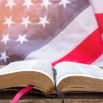 image of an open Bible laying on a table with an American flag in the background