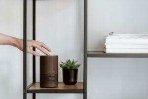 hand reaching out to touch a button on the top of an Amazon Alexa tower