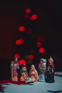 image of a ceramic nativity set on a table with blurred Christmas lights in the background