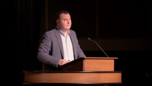 Andrew Gordon standing at chapel podium and looking out at audience