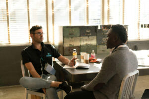 two men sitting down at a table and talking to each other