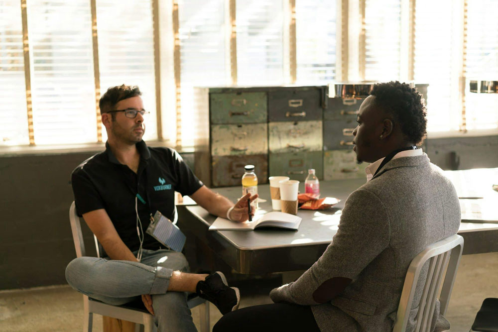 two men sitting down at a table and talking to each other