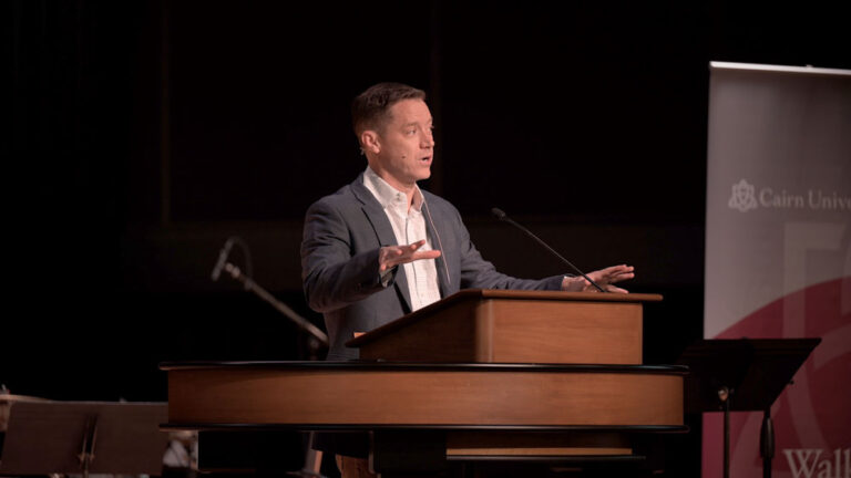 Dr. Joshua Chatraw standing behind chapel podium