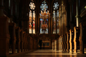 inside of a church looking toward stained glass windows at the top of the aisle