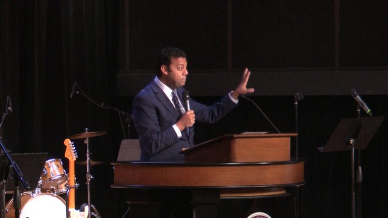 Dr. Ayman Ibrahim behind chapel podium holding a microphone