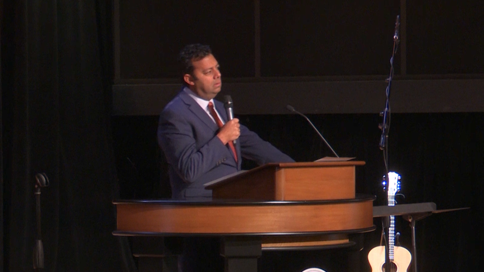 Dr. Ayman Ibrahim behind chapel podium holding a microphone