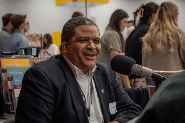 Dr. Keith Plummer smiles as he talks into a podcast mic