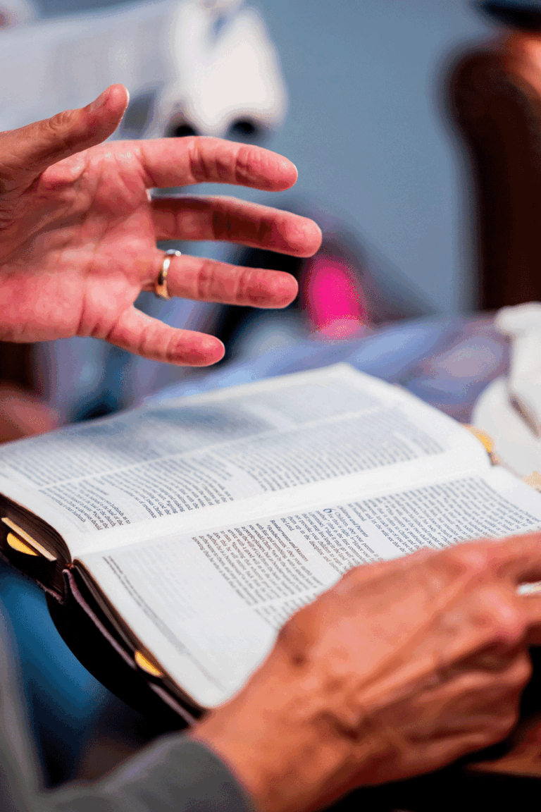 image of a man's hands over an open Bible