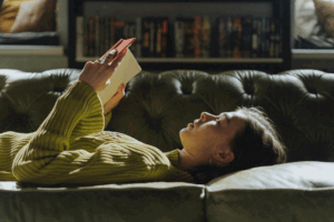 woman lying on a couch holding an open book