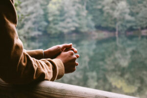 hands folded in prayer leaning on a railing