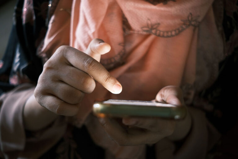 up-close photo of a woman holding a phone in one hand and using her opposite hand to scroll