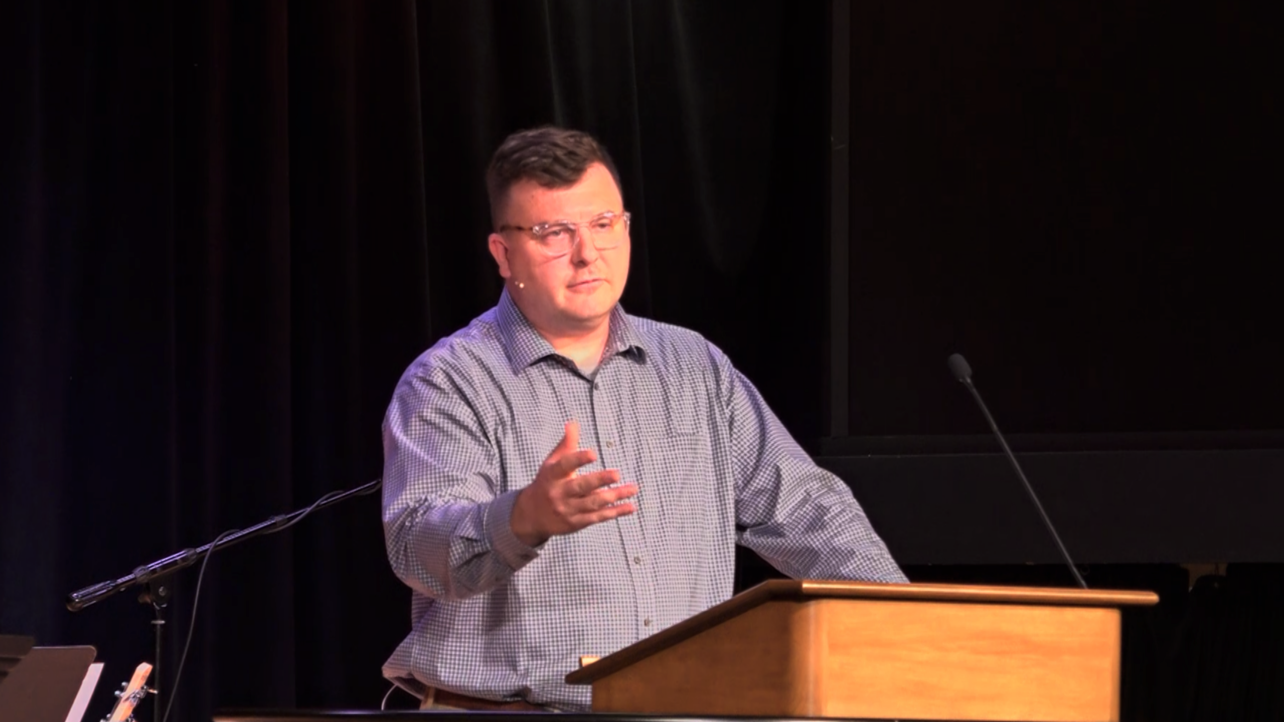 Andrew Gordon standing behind chapel podium with one arm raised in the air