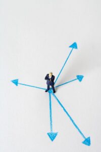 a man standing in a white blank space in the middle of several arrows pointing different directions