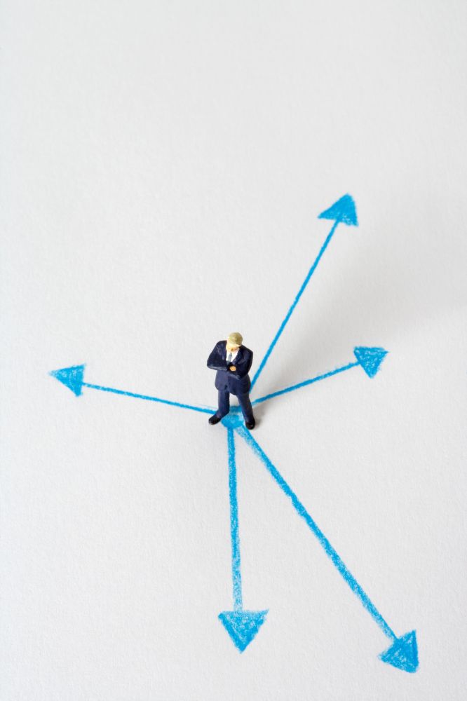 a man standing in a white blank space in the middle of several arrows pointing different directions