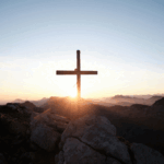 image of a cross on the top of a hillside at sunrise