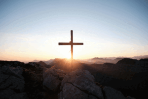 image of a cross on the top of a hillside at sunrise
